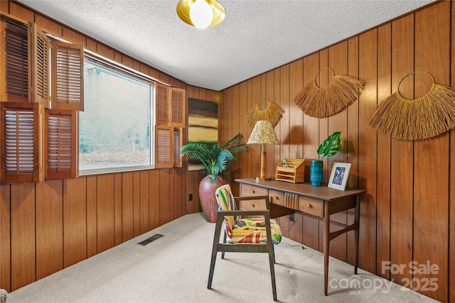 office space featuring a textured ceiling, wood walls, and carpet flooring