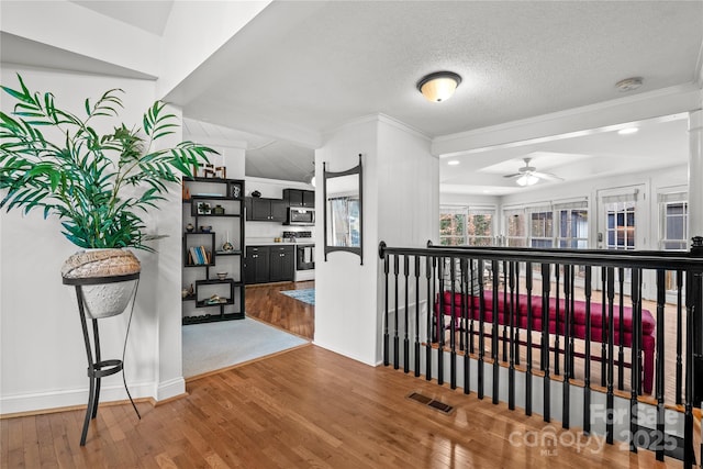 hall with a textured ceiling, crown molding, and hardwood / wood-style flooring