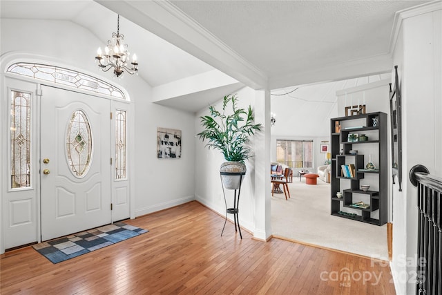 foyer with crown molding, a chandelier, lofted ceiling, and hardwood / wood-style floors