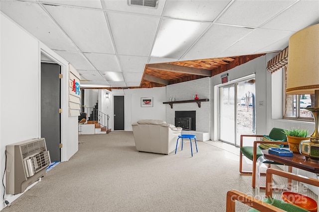 living room featuring carpet floors, a paneled ceiling, a fireplace, and heating unit