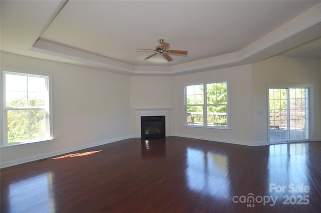 unfurnished living room with dark wood-type flooring, a raised ceiling, and ceiling fan