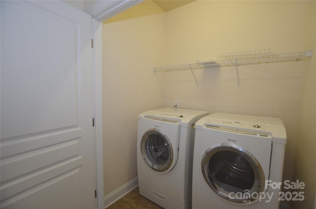 clothes washing area featuring washing machine and dryer and dark tile patterned flooring