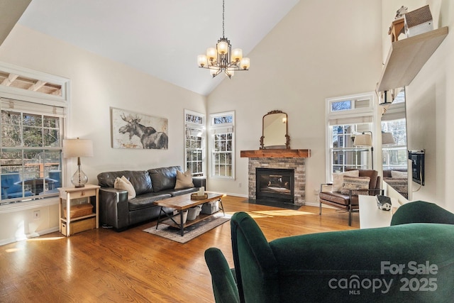 living room featuring a notable chandelier, a stone fireplace, high vaulted ceiling, and hardwood / wood-style flooring