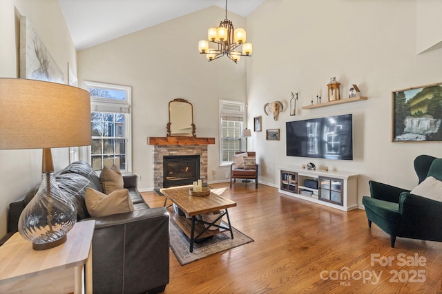 living room with hardwood / wood-style flooring, a fireplace, high vaulted ceiling, and a chandelier