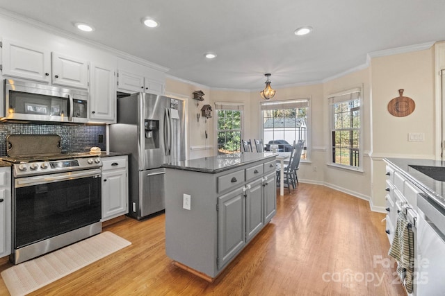 kitchen featuring stainless steel appliances, a center island, light hardwood / wood-style floors, white cabinets, and decorative backsplash