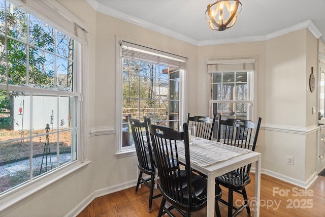 dining area with wood-type flooring, ornamental molding, and a notable chandelier