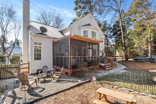 rear view of house with a sunroom and an outdoor fire pit