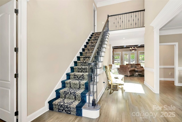 staircase with a notable chandelier, crown molding, french doors, and hardwood / wood-style flooring