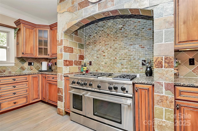 kitchen featuring tasteful backsplash, double oven range, ornamental molding, light stone counters, and light wood-type flooring