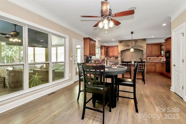 dining space featuring ornamental molding, light hardwood / wood-style floors, and ceiling fan