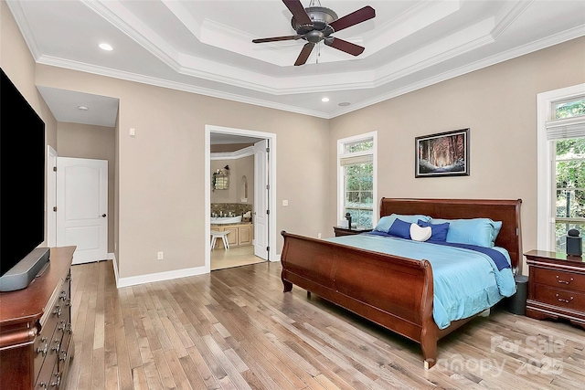 bedroom featuring connected bathroom, a tray ceiling, ceiling fan, and light wood-type flooring