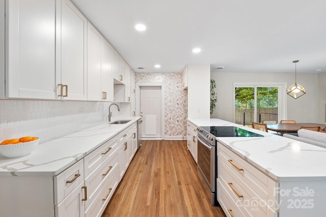 kitchen with stainless steel appliances, hanging light fixtures, light stone countertops, white cabinets, and sink