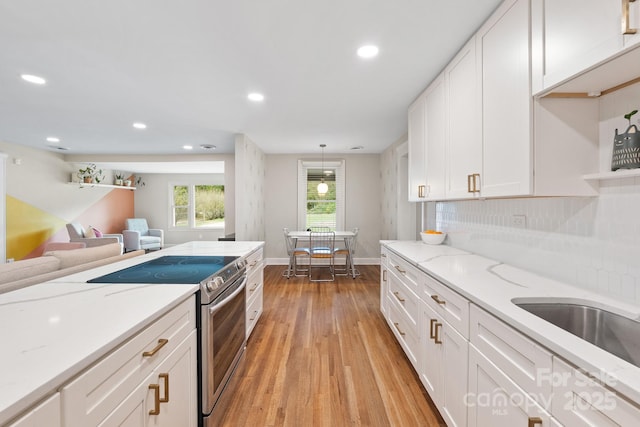 kitchen featuring decorative light fixtures, light stone countertops, stainless steel range with electric cooktop, and white cabinetry