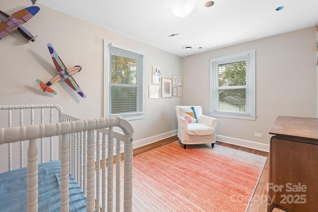 bedroom featuring wood-type flooring and a nursery area