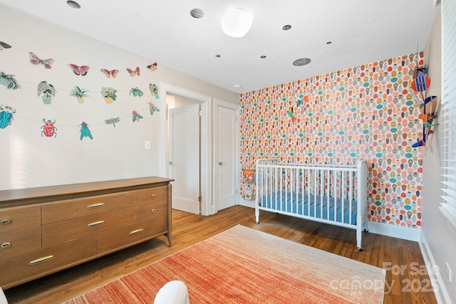 unfurnished bedroom with hardwood / wood-style flooring and a nursery area