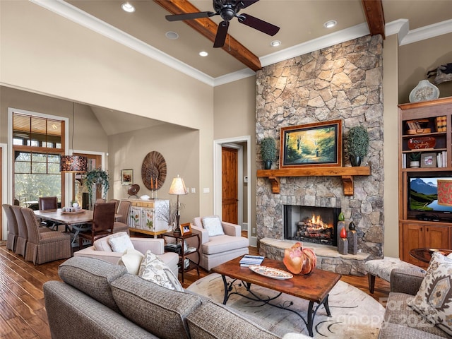 living room with ceiling fan, beam ceiling, wood-type flooring, and a fireplace