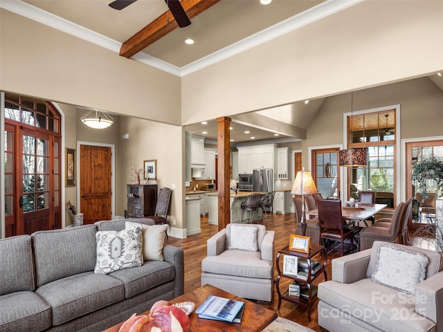 living room with hardwood / wood-style floors, decorative columns, ceiling fan, a high ceiling, and beam ceiling