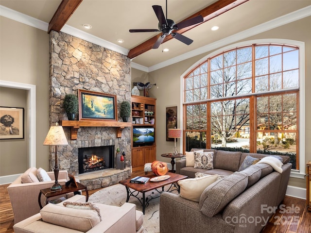 living room featuring a wealth of natural light, wood-type flooring, a stone fireplace, and beamed ceiling