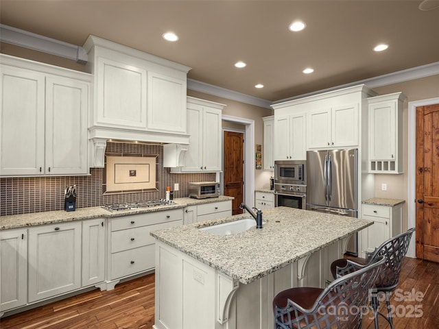 kitchen with appliances with stainless steel finishes, white cabinets, and an island with sink