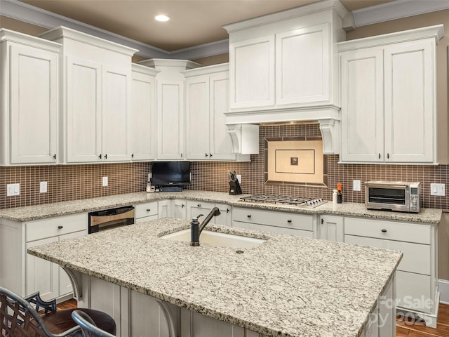 kitchen with light stone counters, a kitchen breakfast bar, and a center island with sink