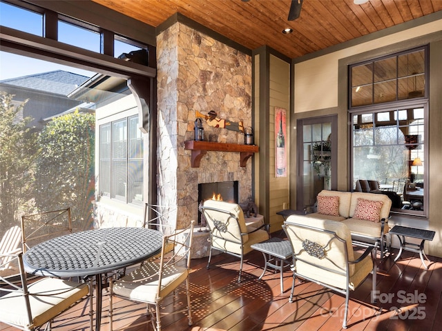 sunroom / solarium featuring ceiling fan, wooden ceiling, a wealth of natural light, and a fireplace