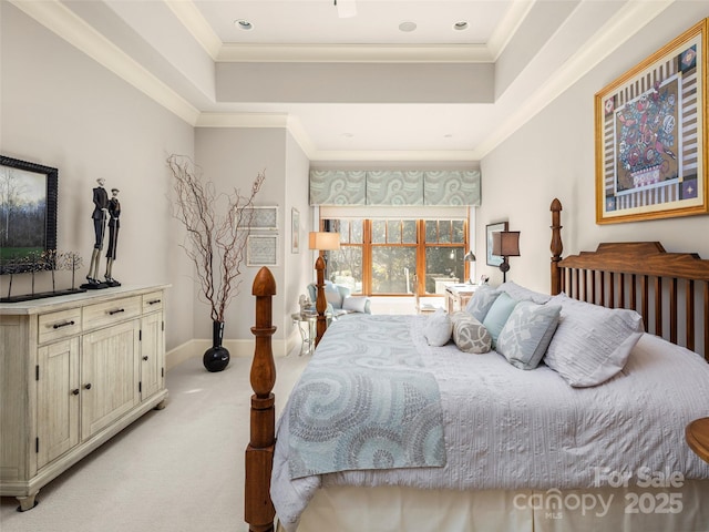 bedroom featuring ornamental molding, light colored carpet, and a tray ceiling