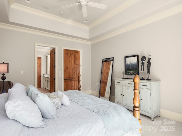 bedroom with ceiling fan, light colored carpet, ensuite bath, a tray ceiling, and ornamental molding