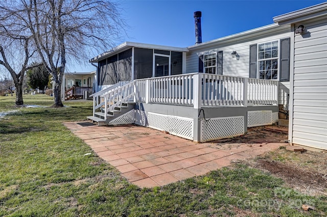 back of property with a patio area, a wooden deck, a sunroom, and a lawn