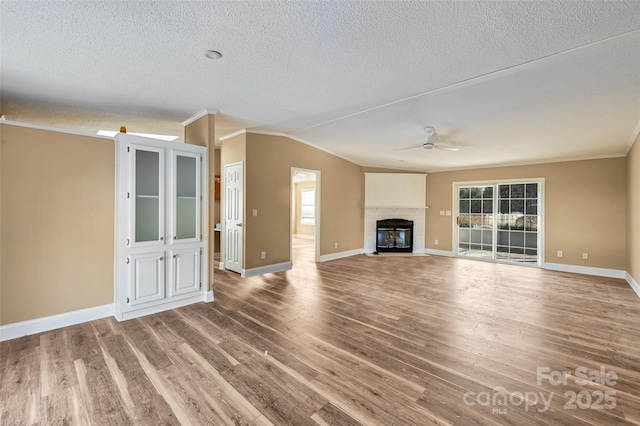 unfurnished living room with vaulted ceiling, ceiling fan, hardwood / wood-style flooring, a textured ceiling, and ornamental molding