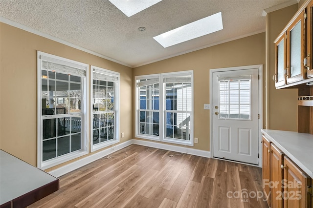 entryway with ornamental molding, hardwood / wood-style floors, a textured ceiling, and vaulted ceiling with skylight