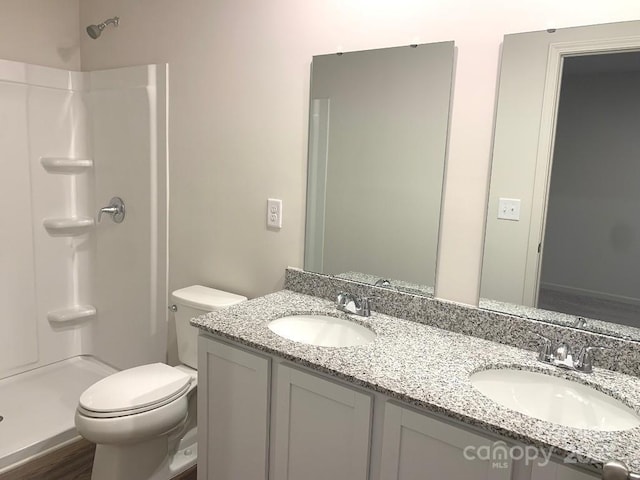 bathroom featuring toilet, wood-type flooring, walk in shower, and vanity