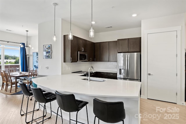 kitchen featuring sink, kitchen peninsula, stainless steel appliances, and dark brown cabinets