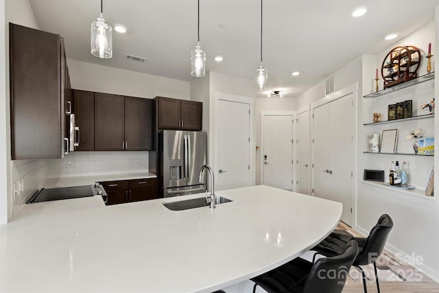 kitchen featuring backsplash, kitchen peninsula, a kitchen bar, sink, and appliances with stainless steel finishes