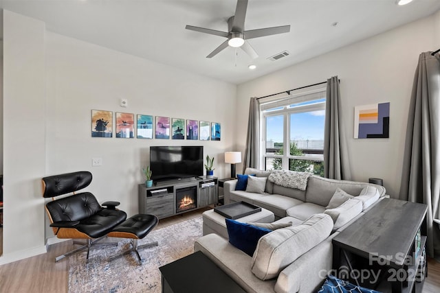 living room with ceiling fan, wood-type flooring, and a fireplace