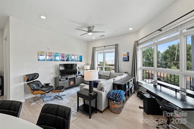 living room with ceiling fan, a fireplace, and light hardwood / wood-style flooring