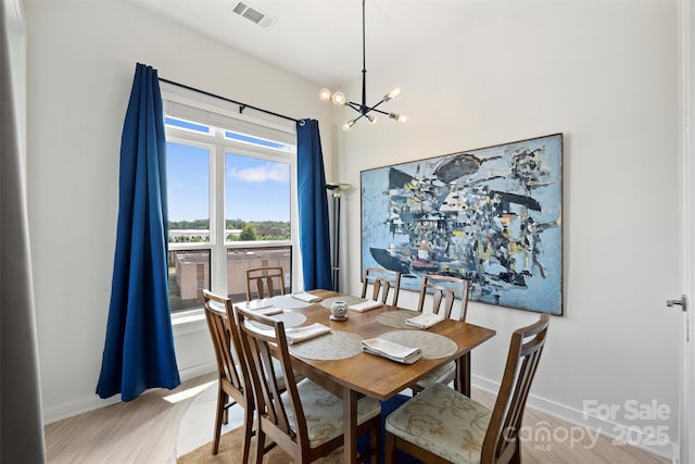 dining space featuring hardwood / wood-style floors and an inviting chandelier