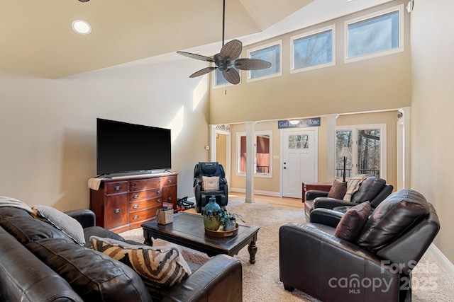 living room featuring decorative columns, ceiling fan, and a high ceiling