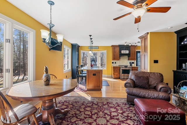 dining space with sink, ceiling fan with notable chandelier, and rail lighting