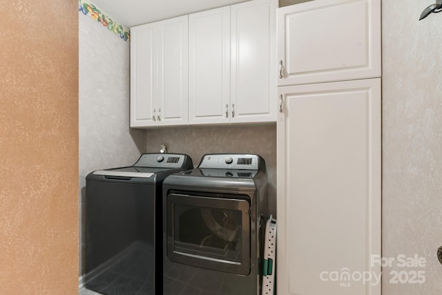 clothes washing area featuring cabinets and washer and clothes dryer