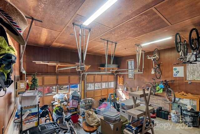 garage featuring a garage door opener, wooden ceiling, and wood walls