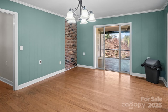 spare room with light wood-type flooring, a notable chandelier, and ornamental molding