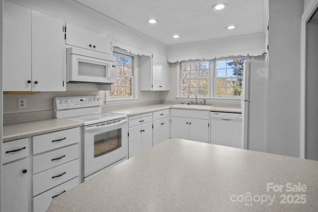 kitchen with sink, white appliances, and white cabinetry