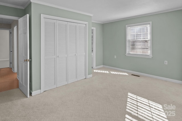 unfurnished bedroom featuring light carpet, a closet, and crown molding