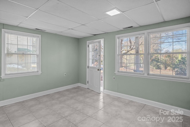 tiled spare room with a paneled ceiling and a healthy amount of sunlight