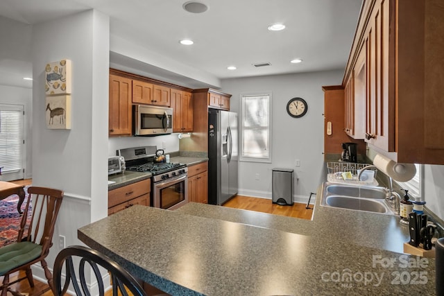 kitchen with appliances with stainless steel finishes, kitchen peninsula, and sink