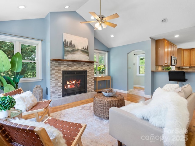 living room with a fireplace, lofted ceiling, light hardwood / wood-style floors, and plenty of natural light