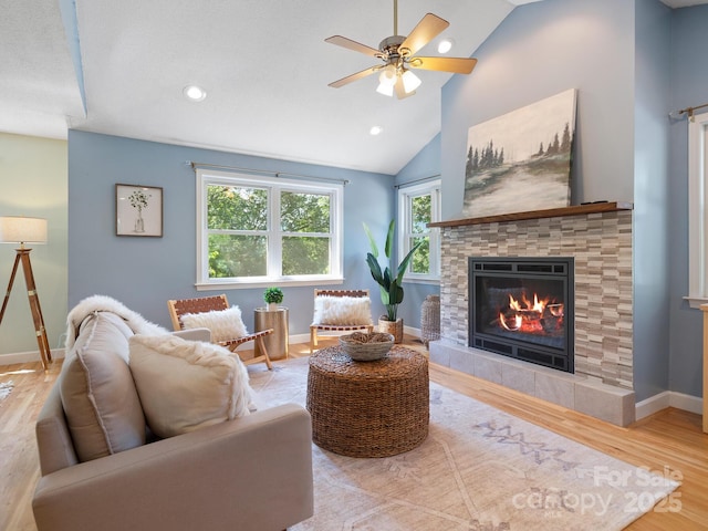 living room with ceiling fan, wood-type flooring, a fireplace, and vaulted ceiling