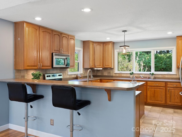 kitchen featuring decorative backsplash, a kitchen breakfast bar, stainless steel appliances, and pendant lighting