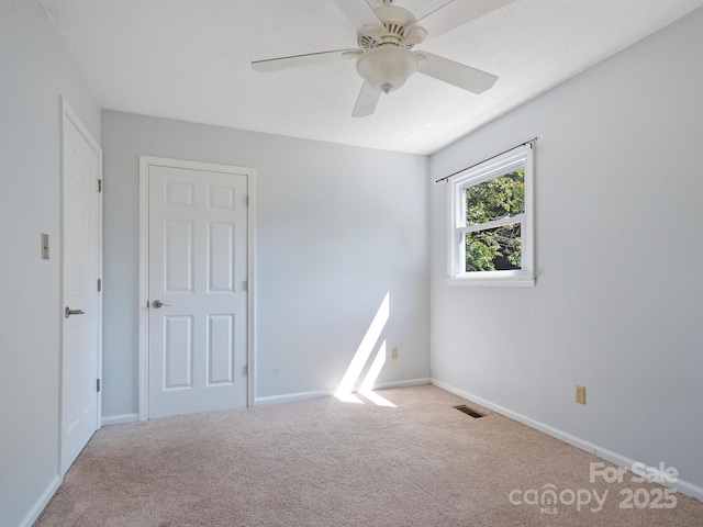 unfurnished room with light carpet, ceiling fan, and a textured ceiling