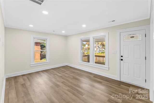 foyer with crown molding and light hardwood / wood-style floors